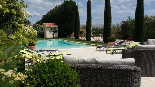 a swimming pool in a yard with wicker chairs at Mas Saint Julien in Cavaillon