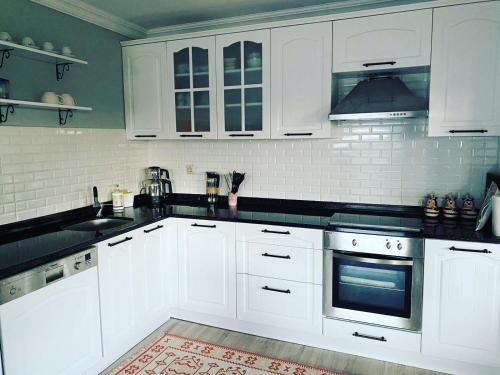 una cocina con armarios blancos y encimeras negras en Trabzon saklı villa en Akcaabat