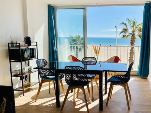 une salle à manger avec une table et des chaises bleues et l'océan dans l'établissement Évasion - superbe vue mer !, à Canet