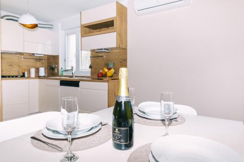 a bottle of wine sitting on a table with glasses at Edonia Garden Home Comfortable & stylish duplex apartment with relaxing private garden in Brodarica