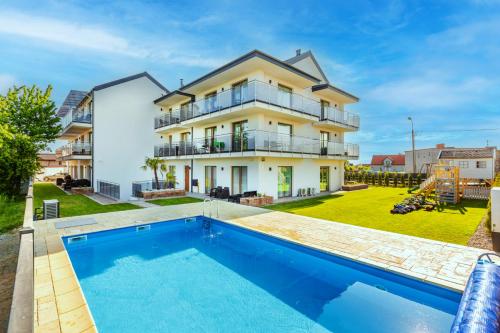 ein Haus mit einem Pool vor einem Haus in der Unterkunft Kashubian Resort in Władysławowo