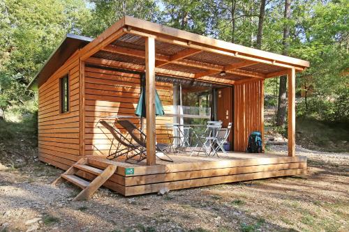 a cabin with a deck with a table and chairs at Huttopia De Meinweg in Herkenbosch