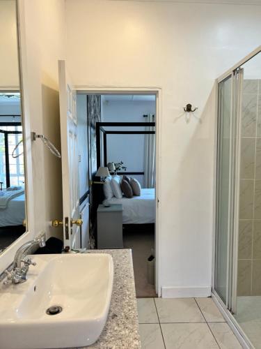 a bathroom with a sink and a bedroom with a bed at Edgehill in Pietermaritzburg