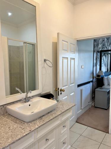 a white bathroom with a sink and a mirror at Edgehill in Pietermaritzburg