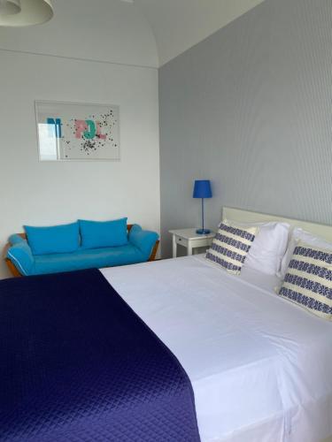 a bedroom with a white bed and a blue couch at Capri Inn in Capri