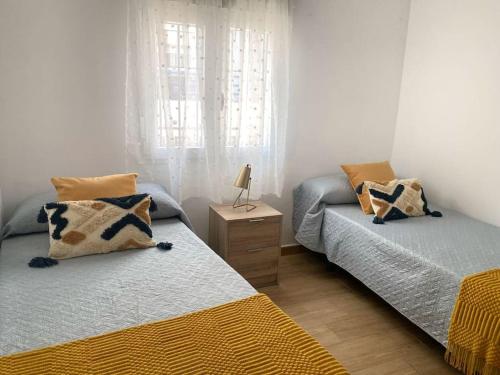 ein Schlafzimmer mit 2 Betten und einem Tisch mit einer Lampe in der Unterkunft Estancia a 600m de la playa en el centro de Punta Umbria in Punta Umbría