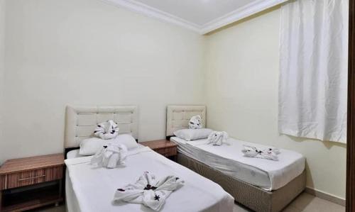 2 camas en una habitación con sábanas blancas y toallas en ALİ ÜNAL APART OTEL, en Alanya