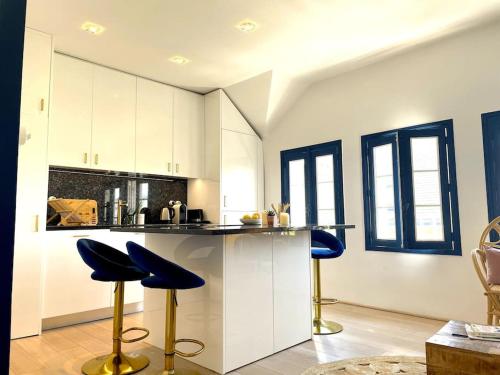 une cuisine avec des placards blancs et des tabourets de bar bleus dans l'établissement Charmant Duplex à 1min La Baule, au Pouliguen