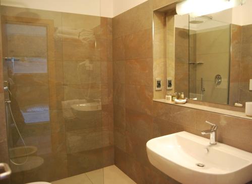 een badkamer met een wastafel en een douche met een spiegel bij Aparthotel Albatros in Lignano Sabbiadoro