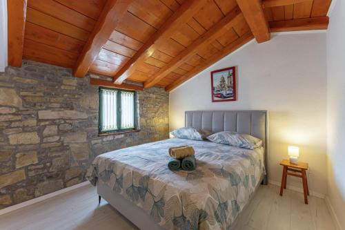 een slaapkamer met een bed en een stenen muur bij Villa Mikales in Čepić - Haus für 8 Personen in Kršan