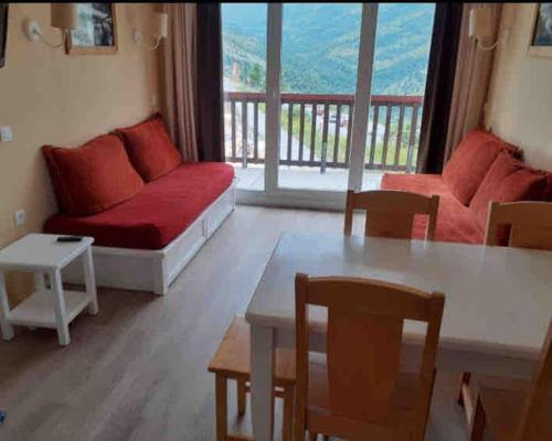 un salon avec un canapé rouge et une table dans l'établissement Appartement pied des pistes Valmeinier, à Valmeinier