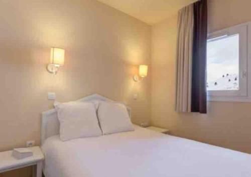 une chambre avec un lit blanc et une fenêtre dans l'établissement Appartement pied des pistes Valmeinier, à Valmeinier