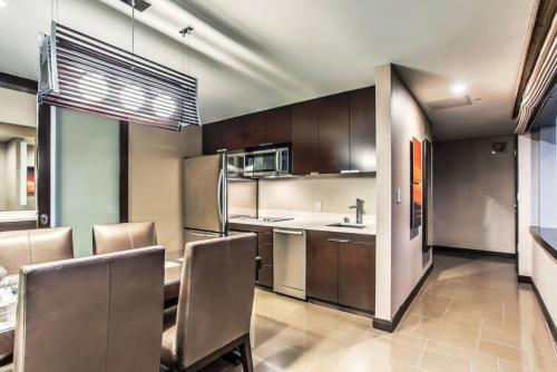 a kitchen with brown cabinets and a table and chairs at City Center - Panoramic Corner Suite at Vdara in Las Vegas