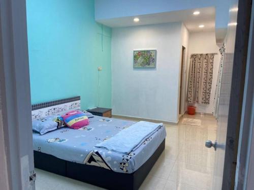 een slaapkamer met een bed met blauwe lakens en kussens bij Homestay Taman Sri Nibong 庆丰园 in Nibung Tebal