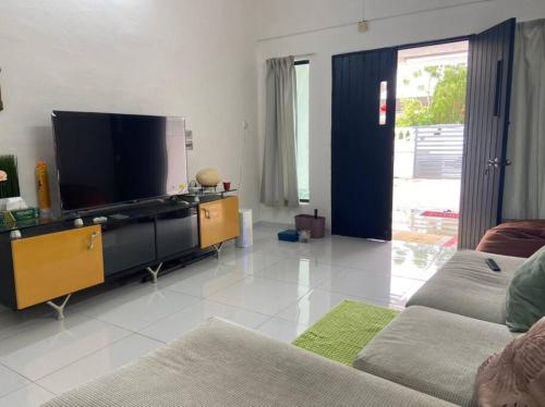 een woonkamer met een grote flatscreen-tv bij Homestay Taman Sri Nibong 庆丰园 in Nibung Tebal