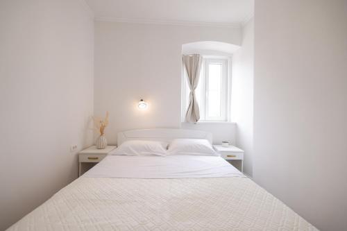 een witte slaapkamer met een wit bed en een raam bij Sea Gate Apartment in Zadar