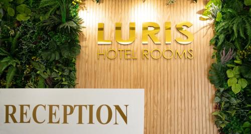 a sign on a wooden wall with plants at Hotel Luris in Golem