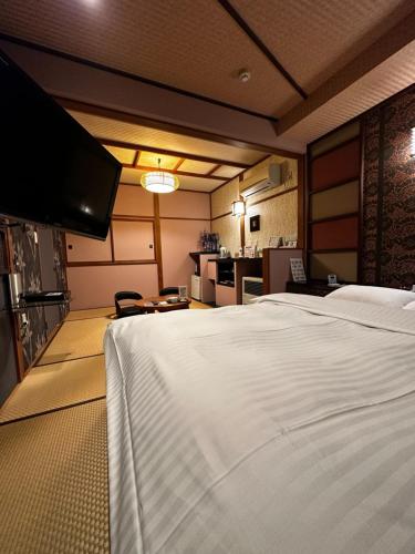 a bedroom with a large white bed and a kitchen at ホテル水明 in Koriyama