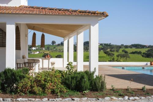 a white house with a pool and a pavilion at Cucumbi in Santa Susana