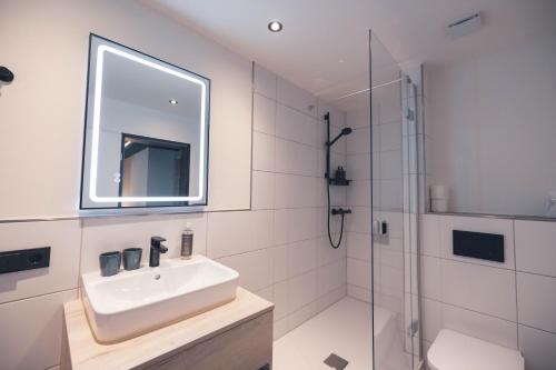 a white bathroom with a sink and a shower at The Oceans in Timmendorfer Strand