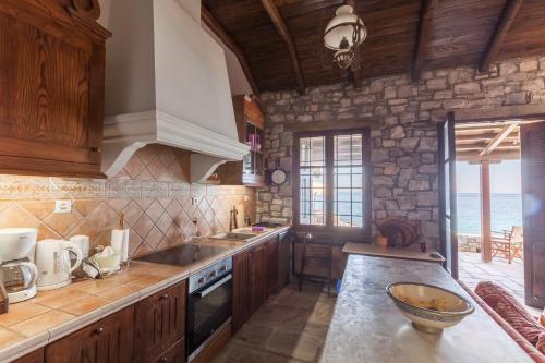 a kitchen with wooden cabinets and a stone wall at Big Blue Pelion in Pilion