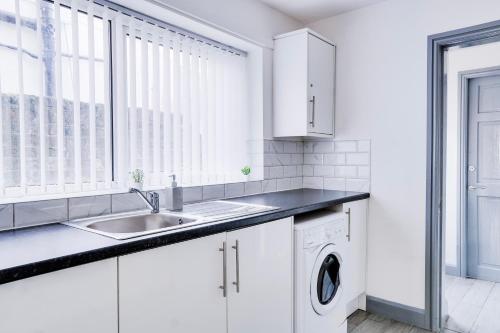 - une cuisine blanche avec un évier et un lave-linge dans l'établissement Cosy 3 bedroom house near Anfield Stadium, à Liverpool