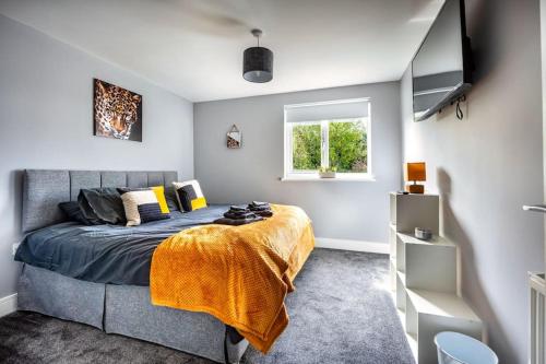 a bedroom with a bed with a yellow blanket and a window at Hudson Apartment in East Kilbride