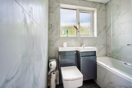 a bathroom with a toilet and a sink and a tub at Hudson Apartment in East Kilbride