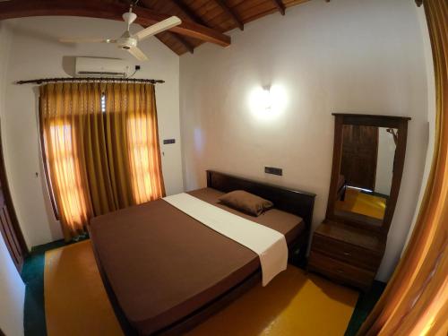 małą sypialnię z łóżkiem i lustrem w obiekcie Sunrise Cabanas w mieście Arugam Bay