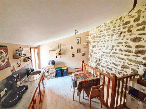een keuken met een stenen muur en een tafel en stoelen bij Gîte des fauvettes in Lorlanges
