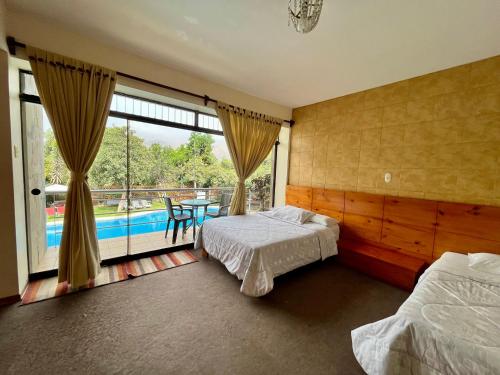 a bedroom with two beds and a view of a pool at Hotel Rumi Wasi in Lunahuaná