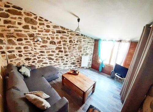 a living room with a couch and a stone wall at Gîte des fauvettes in Lorlanges