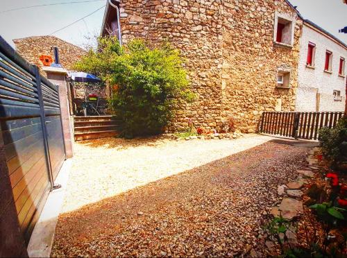 a brick building with a fence next to a yard at Gîte des fauvettes in Lorlanges