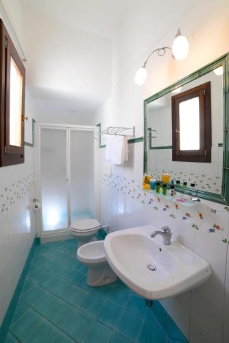 a bathroom with a sink and a toilet and a mirror at Mira Spiaggia in San Vito lo Capo