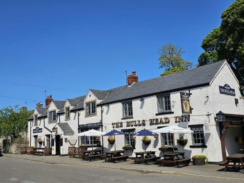 a white building with tables and umbrellas on the street at The Bull at Foolow in Hucklow