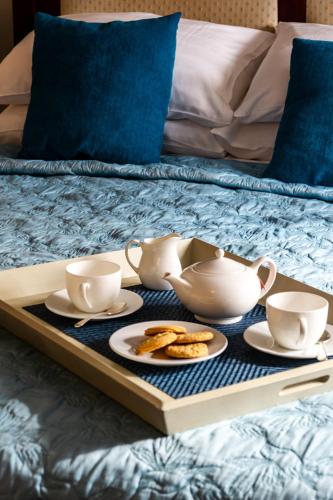 a tray with tea cups and cookies on a bed at The Bull at Foolow in Hucklow