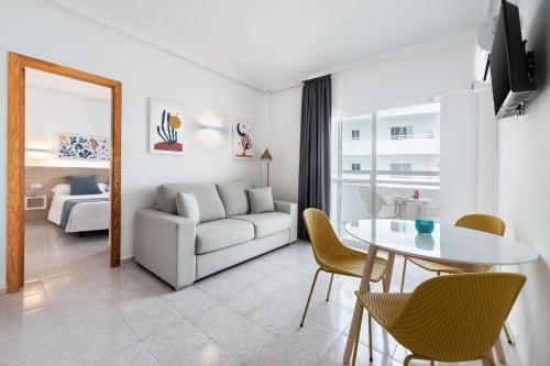 a living room with a white couch and a table at Hotel Apartamentos Vibra Lux Mar in Ibiza Town