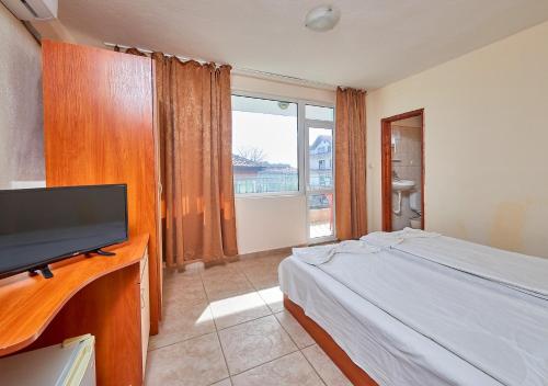 a bedroom with a bed and a flat screen tv at Къща за гости Бор in Pomorie