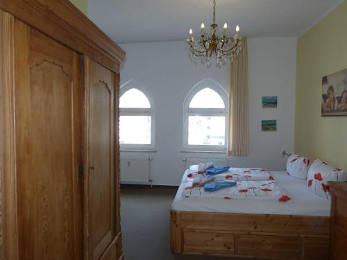 アールベックにあるSchloss Hohenzollern - Fewo mit Meerblickのベッドルーム1室(ベッド1台、窓2つ、シャンデリア付)