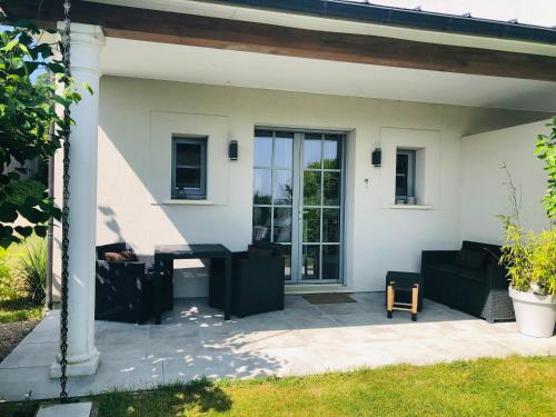 un patio con muebles negros frente a una casa en Bel Air Studios-Terrasse couverte-Jardinet-Vue Pont de Normandie-Parking privé en Honfleur
