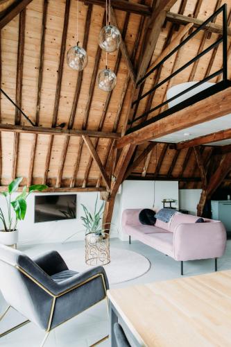 a living room with wooden ceilings and pink furniture at Number 9 holiday apartments in Middelburg