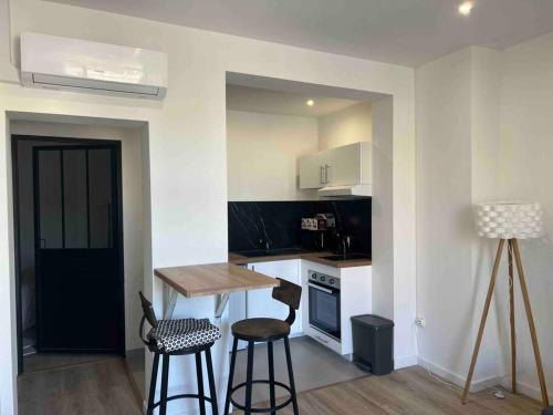 une cuisine avec une table et deux tabourets de bar dans l'établissement Montpellier centre - La Fenêtre de l’écusson, à Montpellier
