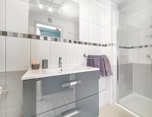 a white bathroom with a sink and a shower at Les Calins d'Honfleur in Honfleur