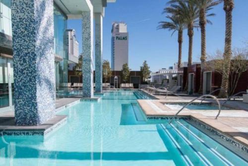a swimming pool with palm trees and a building at Strip View - Luxurious Studio at Palms Place in Las Vegas