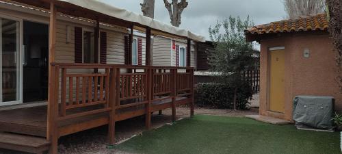 een veranda met een houten terras met een groen gazon bij La Carabasse in Vias
