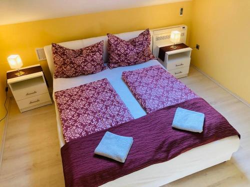 a bedroom with a large bed with purple sheets and pillows at Tóparti Apartmanház in Balatonszárszó