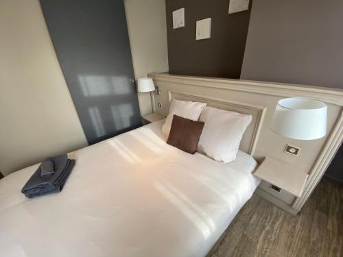 ein Hotelzimmer mit einem Bett mit einem Kissen darauf in der Unterkunft La Pause Voyage in Bourbourg
