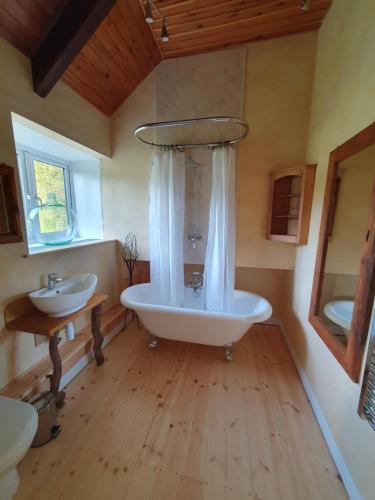 baño grande con bañera y lavamanos en Driftwood Cottage, en Yelverton