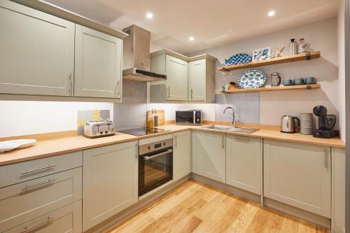 a kitchen with white cabinets and wooden floors at Host & Stay - Breckon Cottage in Whitby
