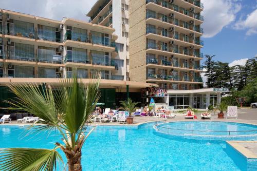 einem Pool mit einer Palme vor einem Gebäude in der Unterkunft Hotel Arda in Sonnenstrand